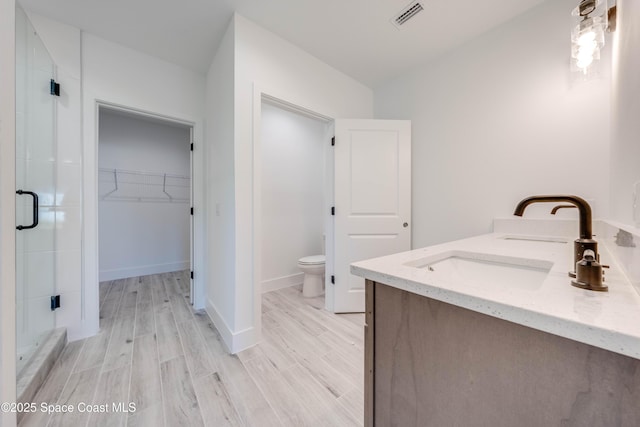 bathroom with toilet, a shower with door, wood-type flooring, and vanity