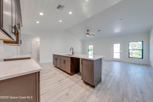 kitchen with ceiling fan, wooden ceiling, a kitchen island with sink, light wood-type flooring, and sink