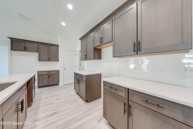 kitchen with tasteful backsplash, light stone countertops, and light hardwood / wood-style flooring