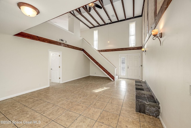 entryway with light tile patterned floors, beamed ceiling, and a high ceiling