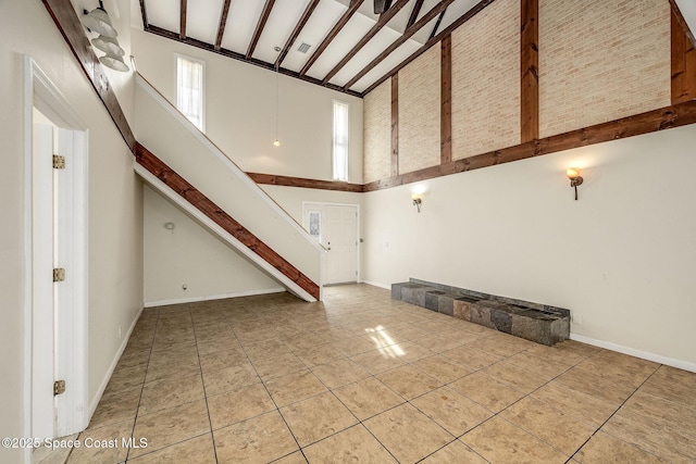 foyer entrance with beamed ceiling, high vaulted ceiling, and light tile patterned floors