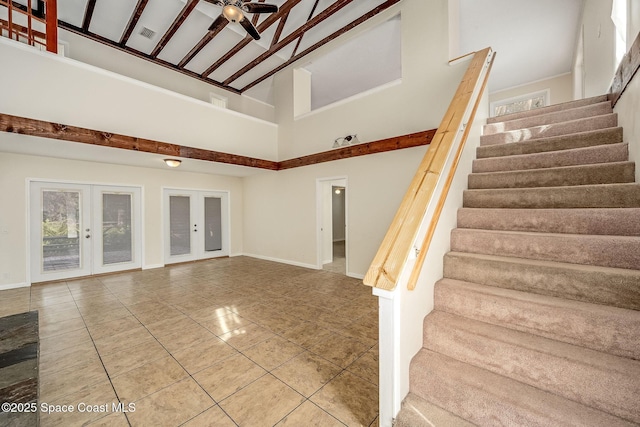 stairs with french doors, ceiling fan, and a high ceiling