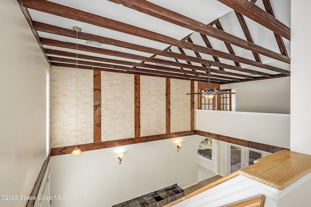 staircase with beam ceiling, high vaulted ceiling, and brick wall