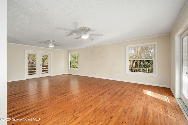 empty room with french doors, crown molding, a textured ceiling, and light wood-type flooring