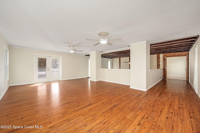 unfurnished living room with ceiling fan, a textured ceiling, light hardwood / wood-style floors, and french doors