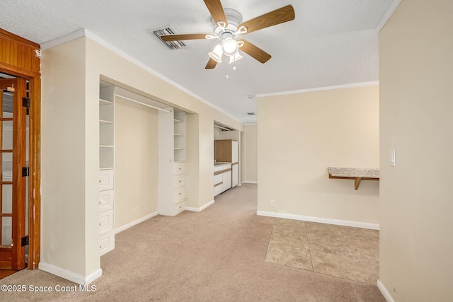 interior space featuring ceiling fan, light colored carpet, ornamental molding, and a textured ceiling