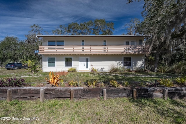 rear view of property with a lawn and a balcony