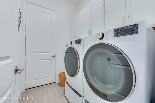 washroom featuring cabinets, independent washer and dryer, and light hardwood / wood-style flooring