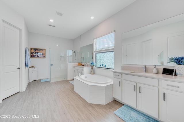 bathroom with independent shower and bath, hardwood / wood-style flooring, and vanity