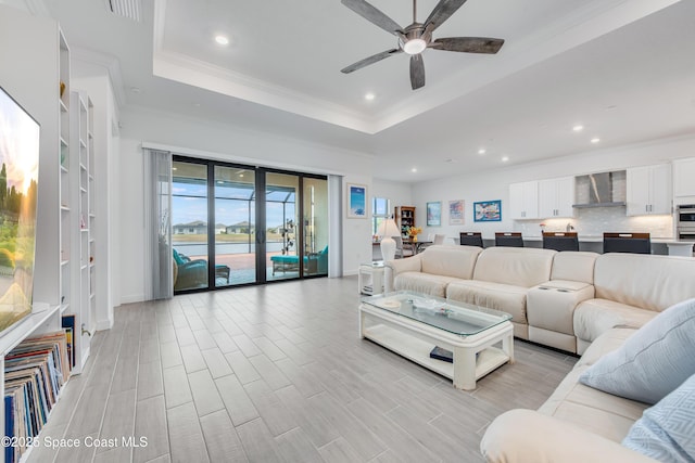 living room featuring french doors, ceiling fan, crown molding, and a raised ceiling