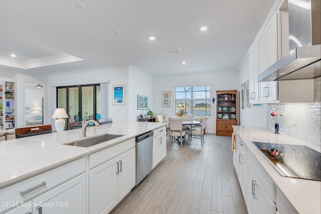 kitchen featuring wall chimney range hood, black electric stovetop, stainless steel dishwasher, sink, and white cabinets