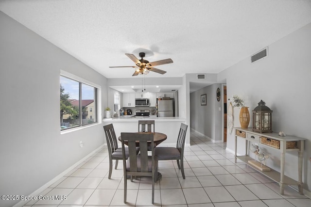 tiled dining area featuring a textured ceiling and ceiling fan