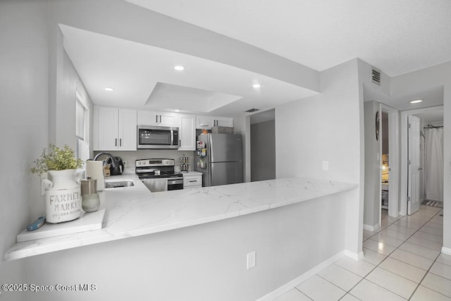 kitchen featuring kitchen peninsula, appliances with stainless steel finishes, light stone countertops, white cabinets, and sink