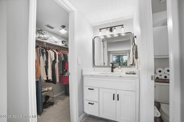 bathroom featuring a textured ceiling, toilet, and vanity