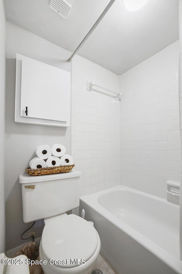 bathroom featuring toilet and tiled shower / bath