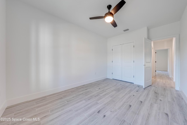 unfurnished bedroom featuring ceiling fan, a closet, and light wood-type flooring