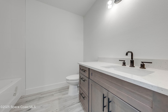 bathroom featuring toilet, vanity, a bathing tub, and hardwood / wood-style flooring