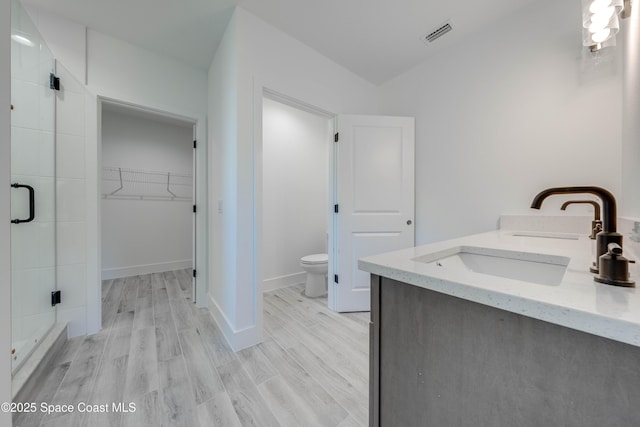 bathroom with toilet, hardwood / wood-style floors, vanity, and an enclosed shower