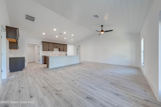 unfurnished living room with ceiling fan, lofted ceiling, light hardwood / wood-style floors, and sink