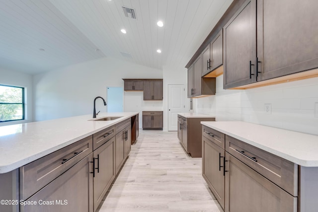 kitchen featuring vaulted ceiling, light hardwood / wood-style floors, sink, an island with sink, and wooden ceiling