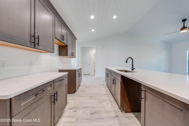 kitchen with lofted ceiling, wood ceiling, decorative backsplash, sink, and light hardwood / wood-style flooring