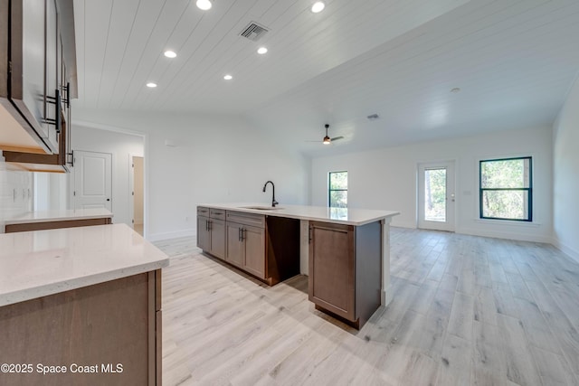 kitchen featuring a wealth of natural light, sink, light wood-type flooring, ceiling fan, and a center island with sink