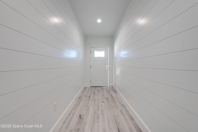 doorway to outside featuring wood walls and light hardwood / wood-style flooring