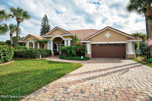 mediterranean / spanish home featuring a garage and a front yard