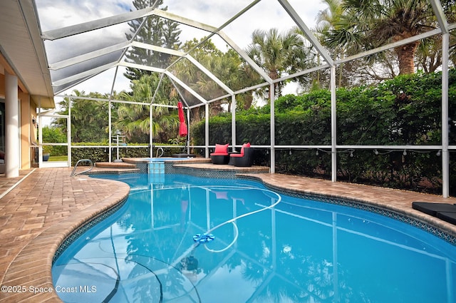 view of pool with a lanai, a patio area, and an in ground hot tub