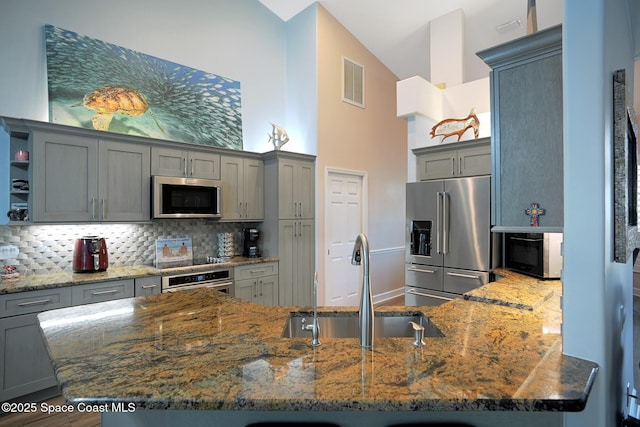 kitchen featuring gray cabinets, appliances with stainless steel finishes, sink, and dark stone countertops