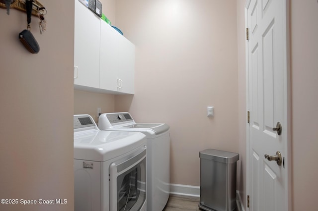 washroom featuring cabinets, independent washer and dryer, and dark hardwood / wood-style floors