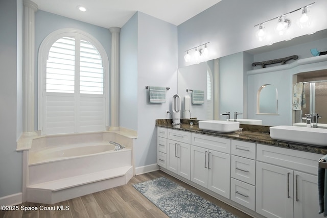 bathroom featuring wood-type flooring, plus walk in shower, and vanity