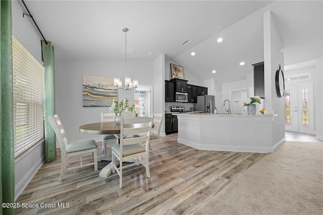 kitchen with an inviting chandelier, light hardwood / wood-style floors, appliances with stainless steel finishes, light stone counters, and sink