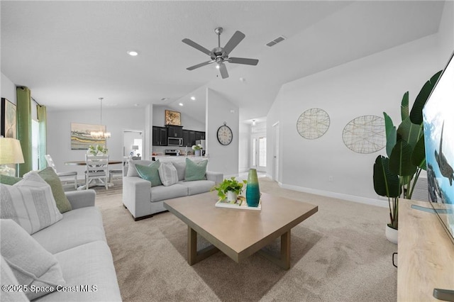 carpeted living room with vaulted ceiling, ceiling fan with notable chandelier, and plenty of natural light