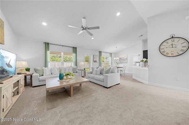 living room with ceiling fan with notable chandelier, lofted ceiling, and light colored carpet