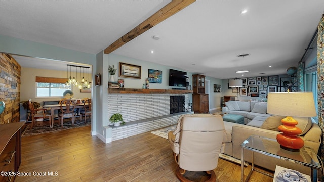 living room featuring hardwood / wood-style floors, beam ceiling, and a fireplace