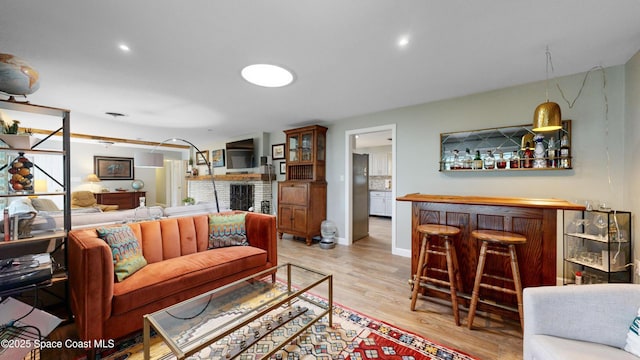 living room with bar and light wood-type flooring