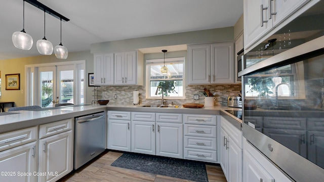 kitchen with sink, stainless steel dishwasher, white cabinets, and decorative light fixtures