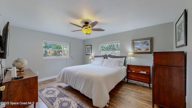 bedroom featuring ceiling fan, light hardwood / wood-style floors, and multiple windows