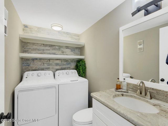 bathroom featuring toilet, washing machine and dryer, and vanity