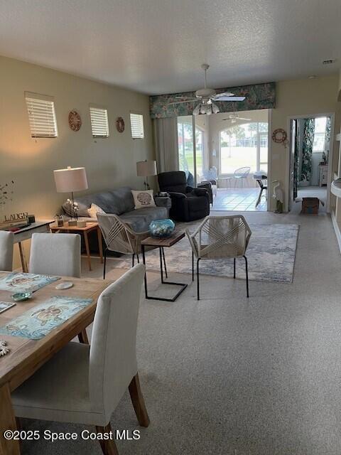 living room with ceiling fan and a textured ceiling