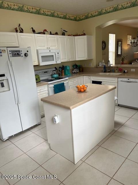 kitchen featuring sink, white appliances, a kitchen island, white cabinets, and light tile patterned flooring