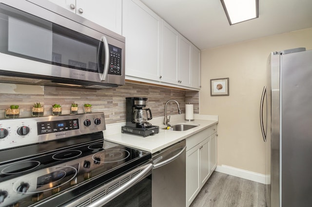 kitchen featuring light wood-type flooring, appliances with stainless steel finishes, white cabinets, and sink