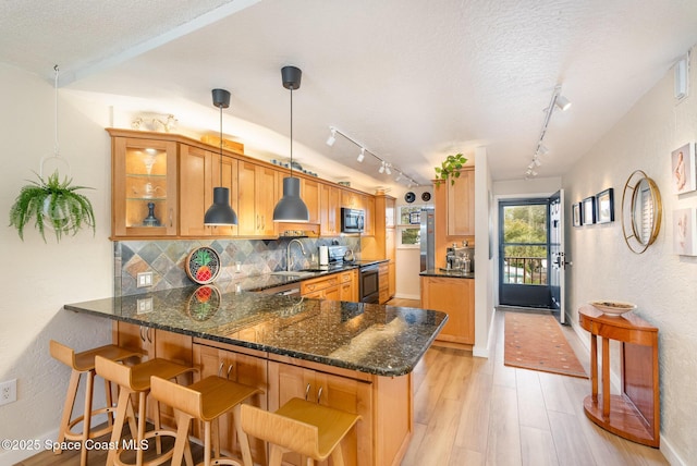 kitchen with kitchen peninsula, electric range, decorative light fixtures, a textured ceiling, and light hardwood / wood-style flooring