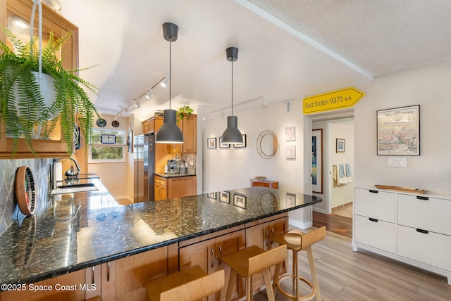 kitchen featuring a kitchen bar, hanging light fixtures, light hardwood / wood-style flooring, and kitchen peninsula