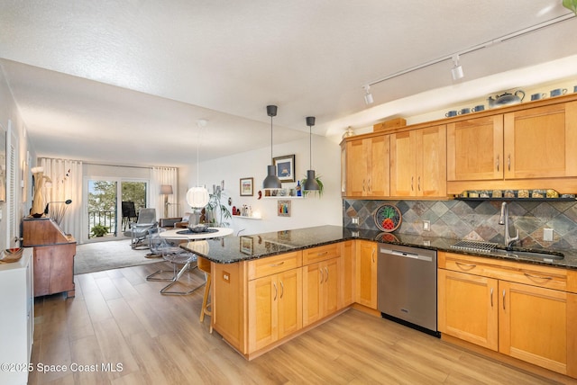 kitchen with kitchen peninsula, decorative light fixtures, dark stone counters, stainless steel dishwasher, and sink