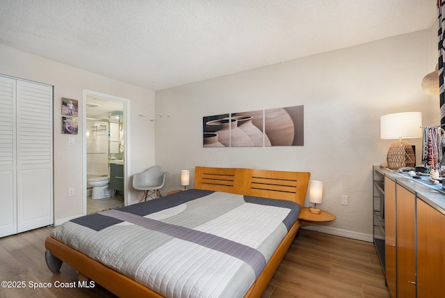 bedroom with hardwood / wood-style flooring, connected bathroom, and a textured ceiling