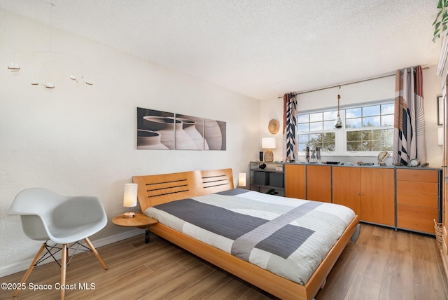 bedroom with light hardwood / wood-style floors and a textured ceiling