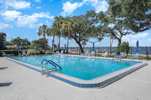 view of swimming pool with a patio area and a water view