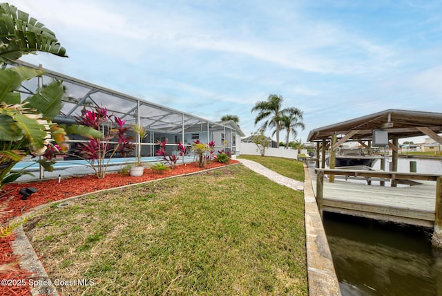 view of yard with a water view, a dock, and glass enclosure